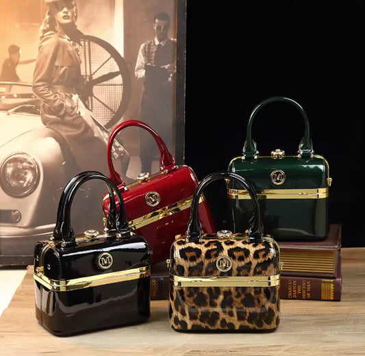 Four handbags in different colors and designs on a wooden surface with a vintage car and people in the background.