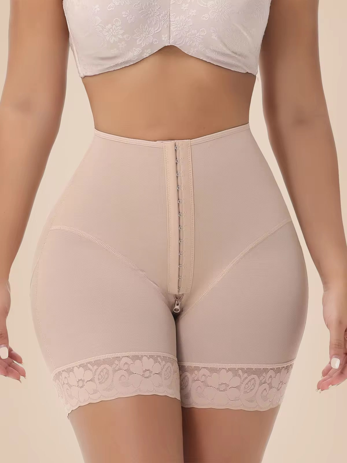 Beige shapewear with lace trim worn by a person on a beige background